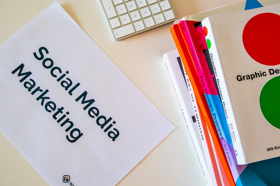 A top view of social media marketing text alongside graphic design books and a keyboard.