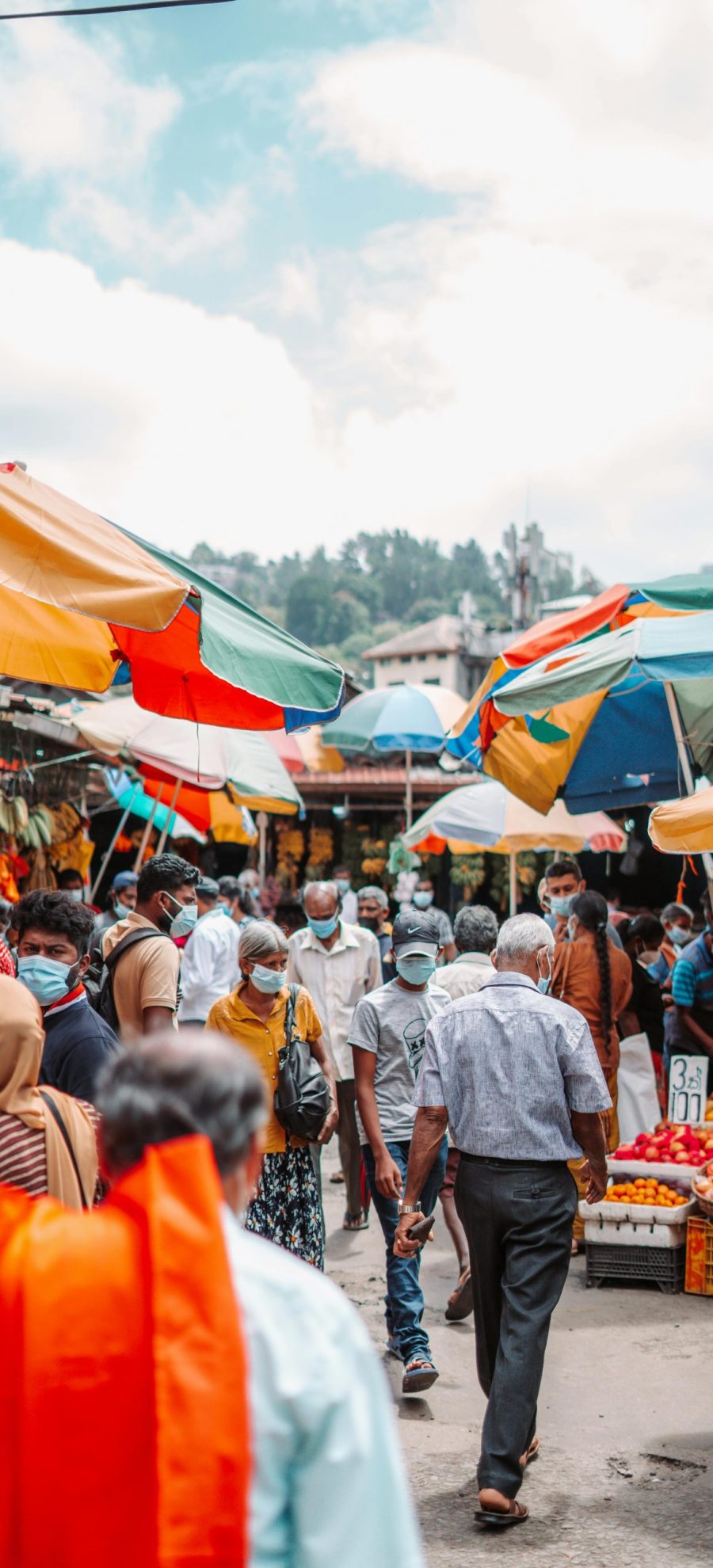 Bustling outdoor market in Sri Lanka with diverse crowd and colorful umbrellas.